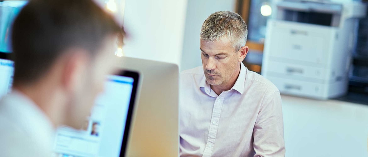 To mænd ved hver deres computer