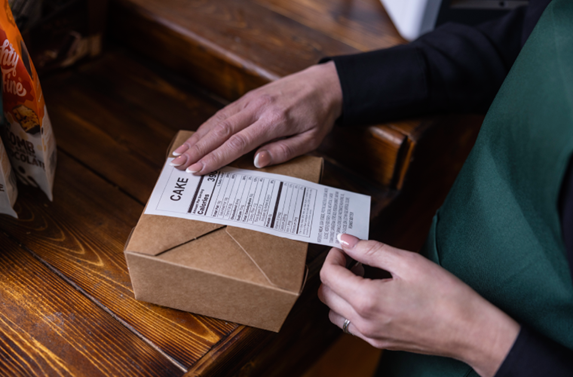 A linerless label being applied to a takeaway food item.