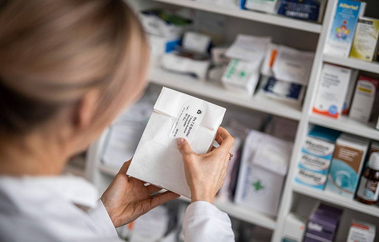 Kvinde, der sætter en label på en medicinpose