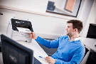 mand sidder ved skrivebord fax