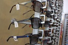 Briller med prisskilte, der hænger på væggen i en optikerbutik 